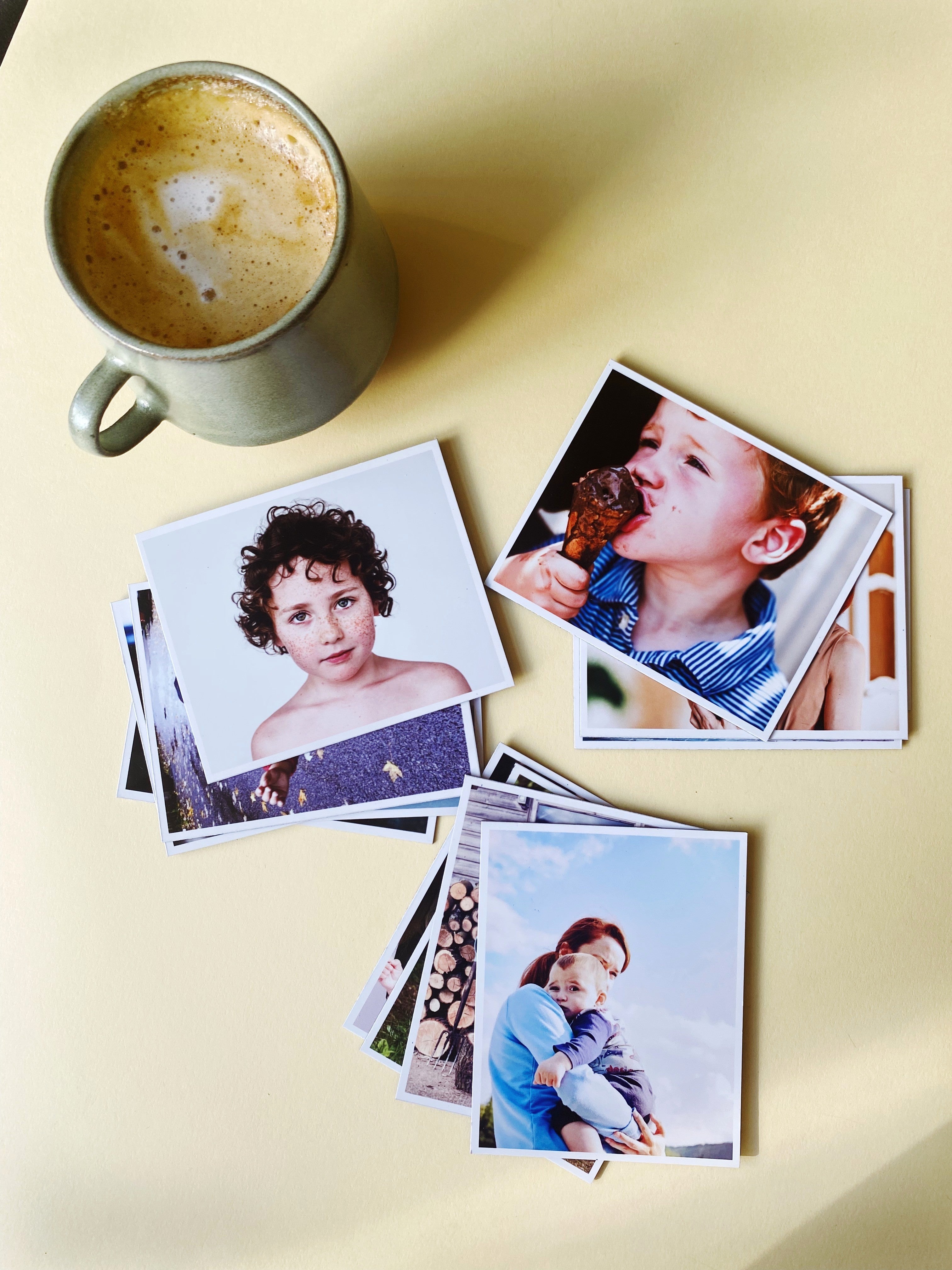 Flat lay of Magnetic Love photo magnets beside a coffee cup, showing printed family memories on a beige background.