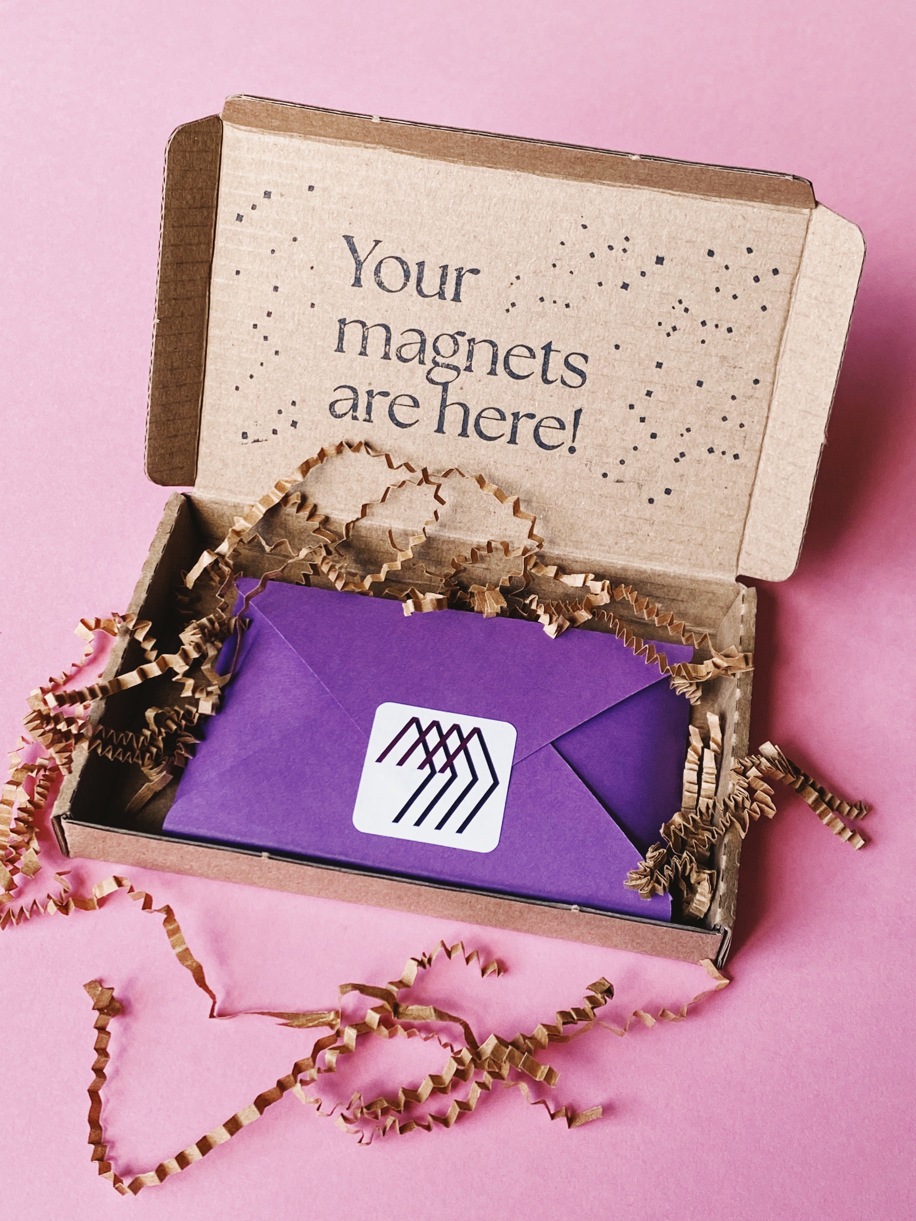Open Magnetic Love gift box with a purple envelope and the message “Your magnets are here!”, symbolizing delivery and customer contact.