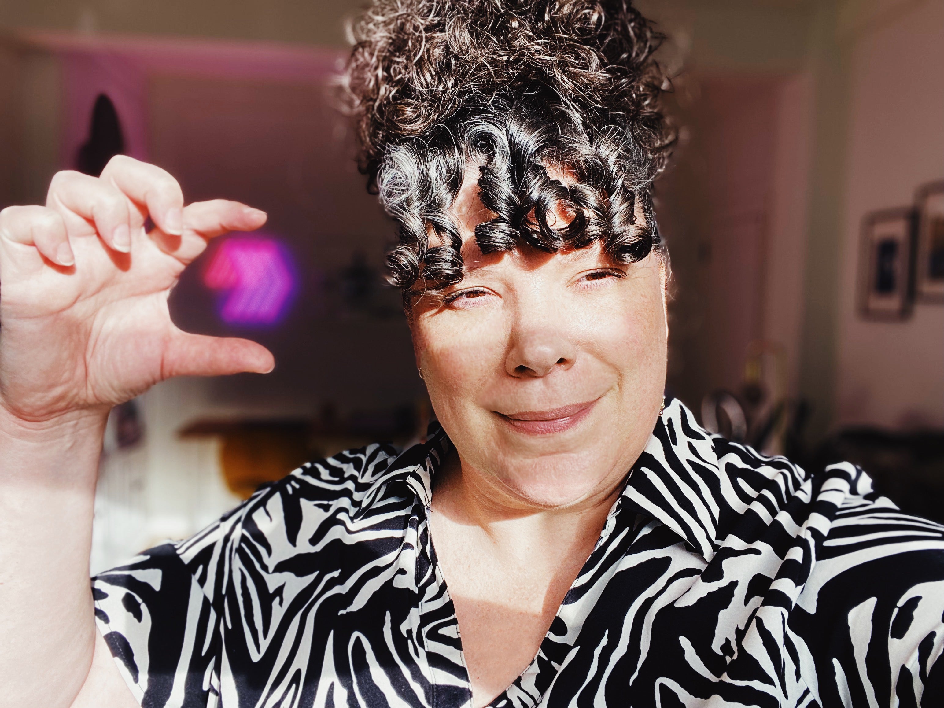 Annie Bérubé, founder of Magnetic Love, smiling in her home studio with the brand’s neon logo in the background – photo from the FAQ contact section.