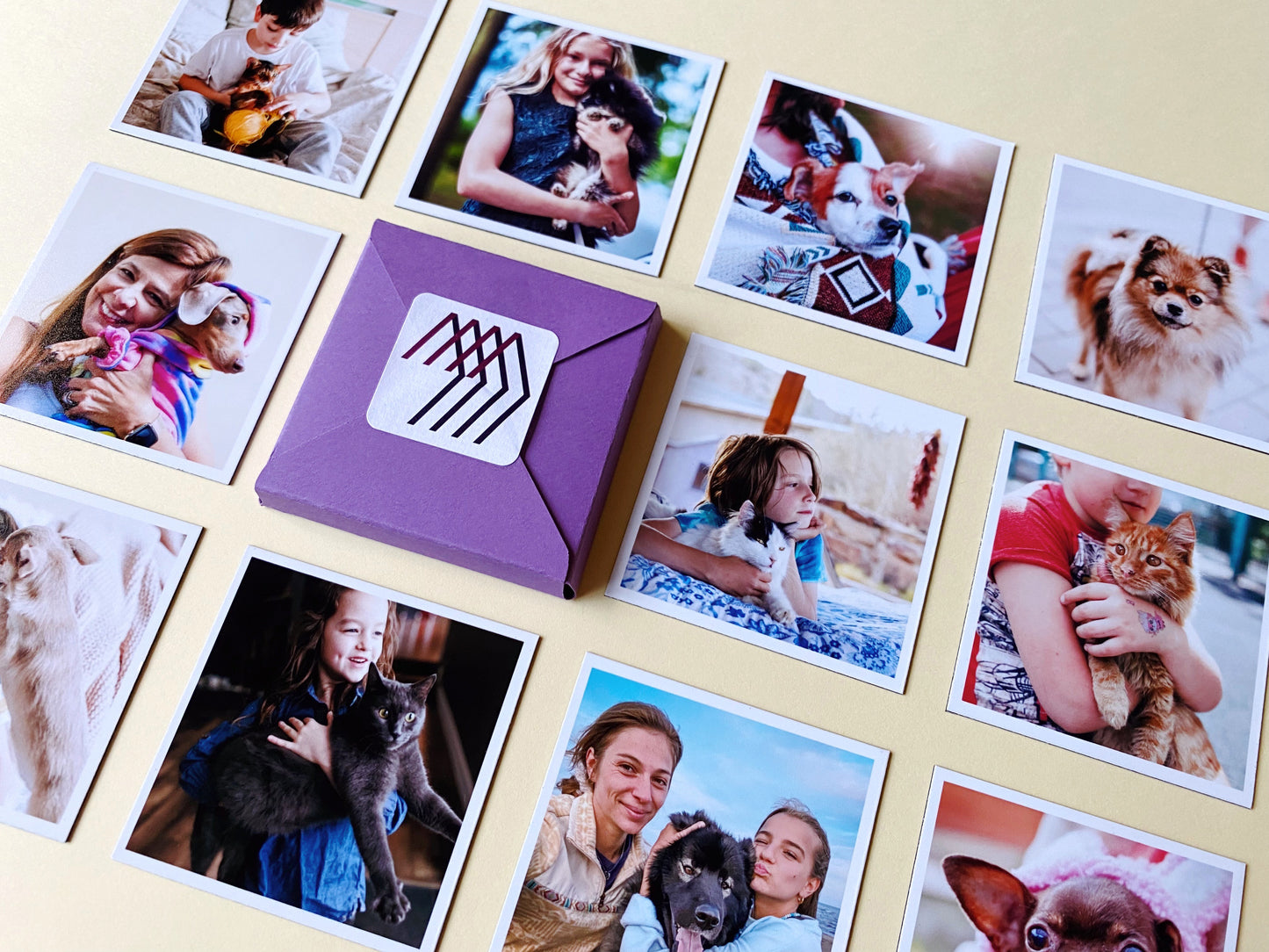 Square custom photo magnets arranged around a Magnetic Love envelope, showing family and pet memories.